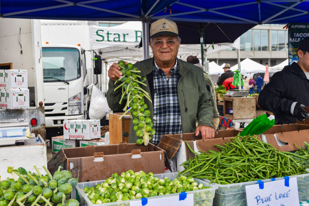 Louis Iacopi holding Brussels sprouts at the Ferry Plaza Farmers Market