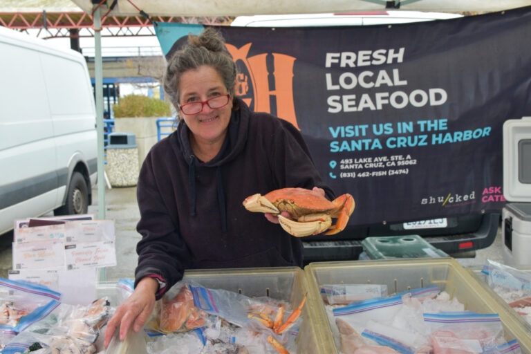 Someone holds up a crab at a farmers market stand