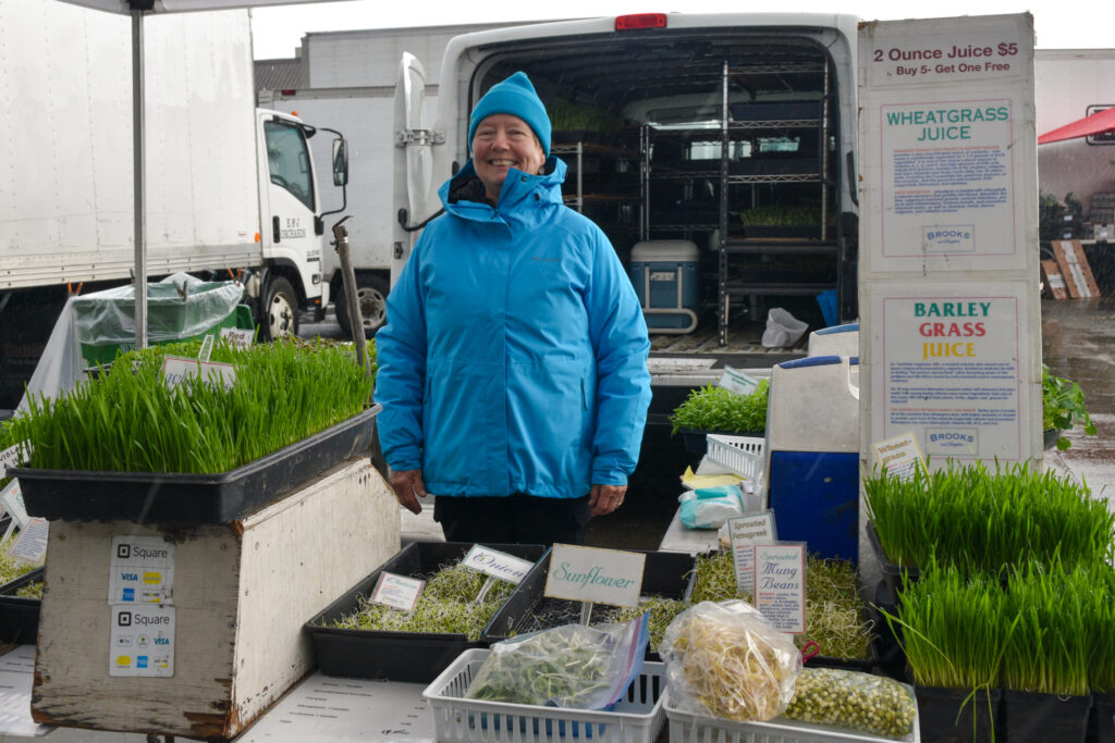 Denise Anderson poses behind a table full of sprouts and microgreens at Brooks and Daughters' stand at the Ferry Plaza Farmers Market in San Francsico