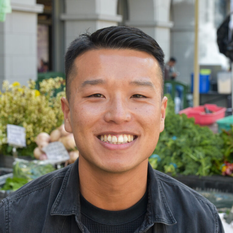 Tommy Phung headshot with Foodwise's Ferry Plaza Farmers Market in the background