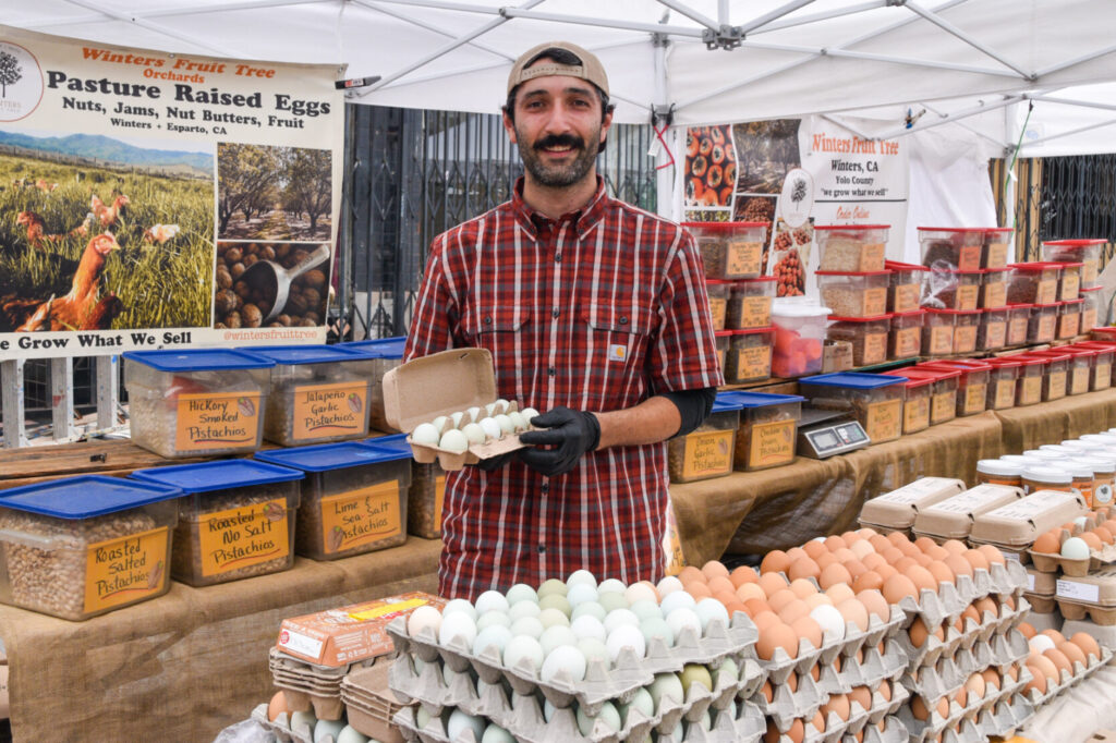 Phil Jr holding a carton of eggs at Winters Fruit Tree's stand at Mission Community Market