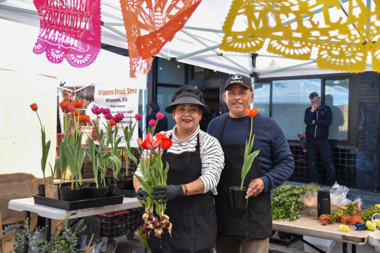 Rosa and David Medrano hold tulips at Medrano's Flowers' stand at Foodwise's Mission Community Market in San Francisco