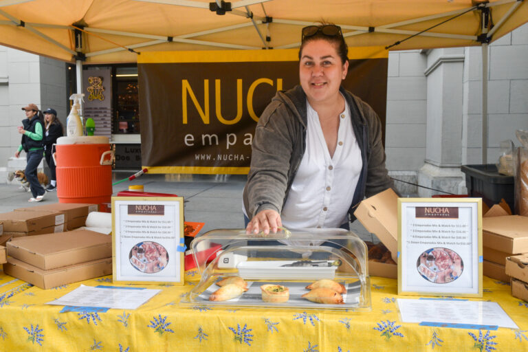 Someone opens a tray of empanadas at Nucha Empanadas' stand at the Ferry Plaza Farmers Market.