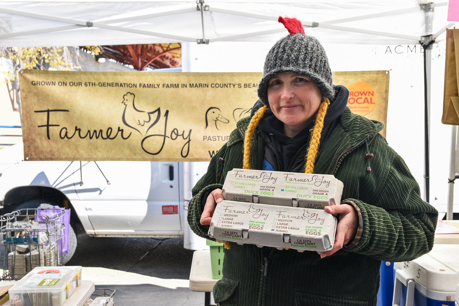 Farmer Joy Dolcini, holding egg cartons, at her stand at FPFM