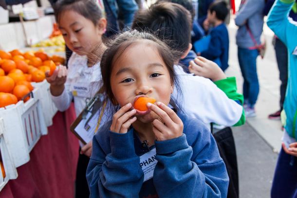 Child eating orange wedge at the Ferry Plaza Farmers Market