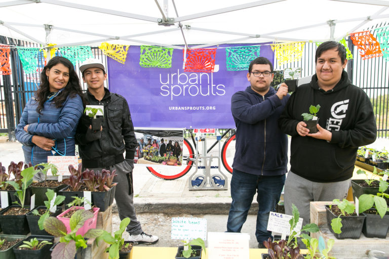 Four people pose at Urban Sprouts' stand at the Mission Community Market.