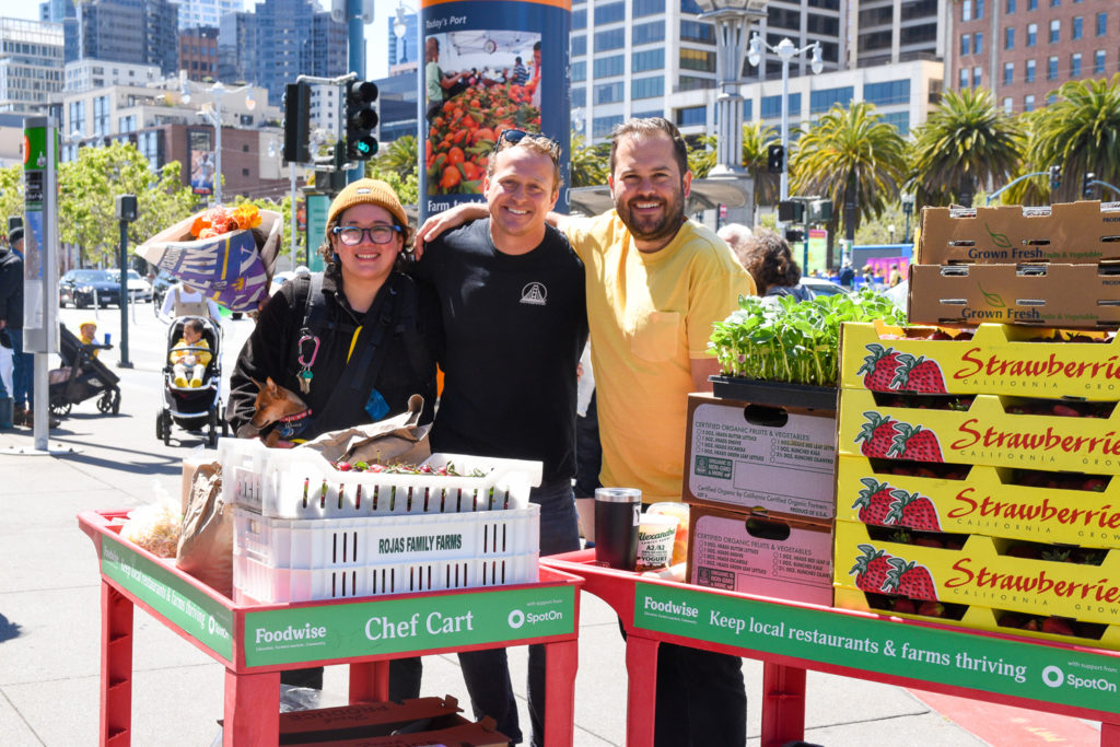 Group photo of three chefs with carts filled with produce at the Ferry Plaza Farmers Market