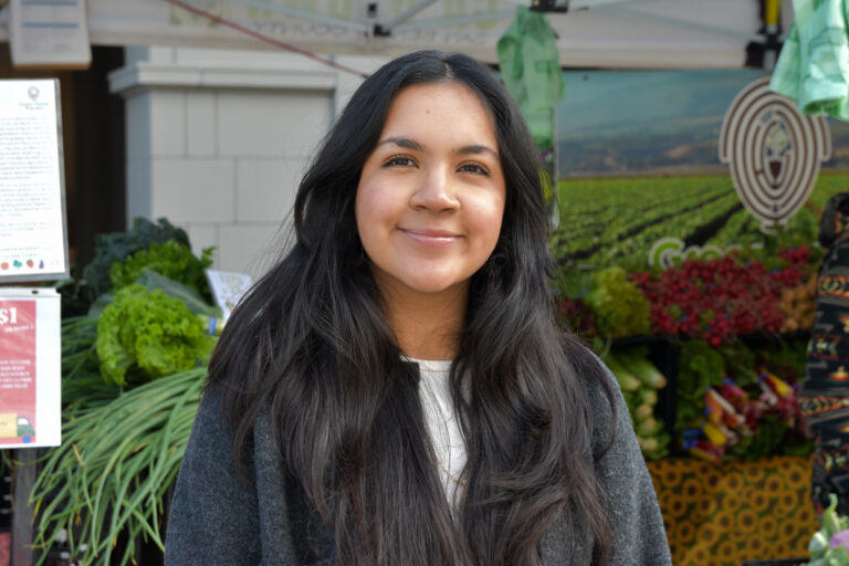 Photo of Nesley Rojo, in front of a stand at Foodwise's Ferry Plaza Farmers Market
