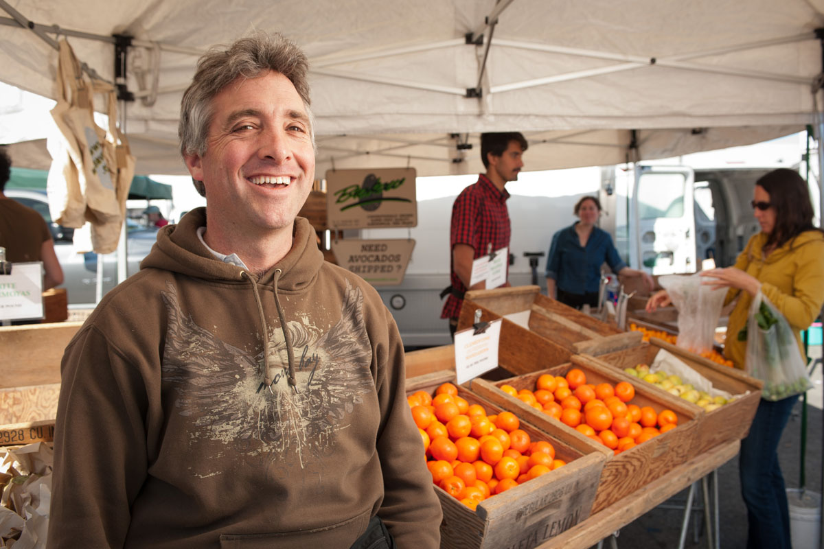 Will Brokaw poses in front of crates of fruit at Brokaw Ranch Company's stand at the Ferry Plaza Farmers Market in San Francisco.
