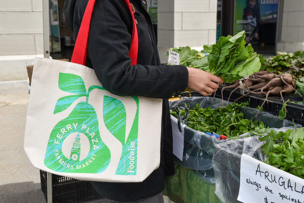Shopper using Foodwise Ferry Plaza Farmers Market tote bag