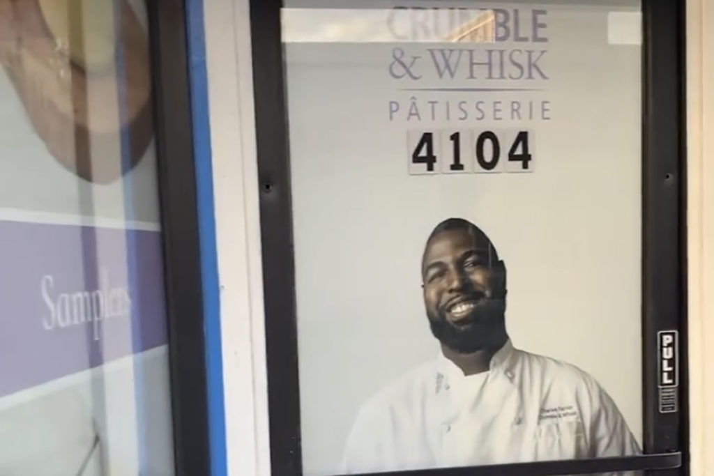 The front door of Crumble and Whisk's storefront, covered with a poster that reads "Crumble and Whisk" and has a picture of Charles.