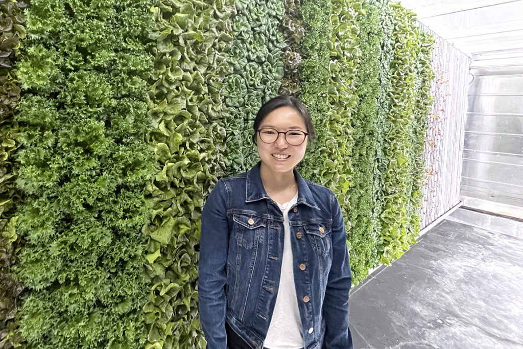 Jiwon Jun, a previous intern, stands in front of a vertical garden
