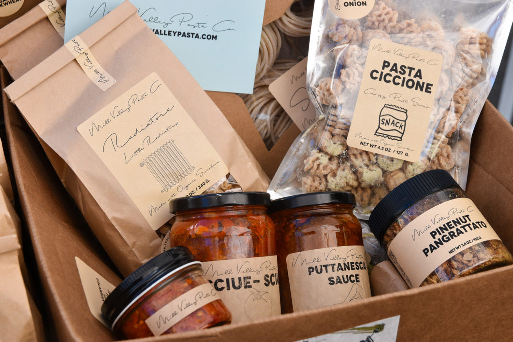 Box of products from Mill Valley Pasta Co, including bags of dried pasta, sauce jars, and toppings.