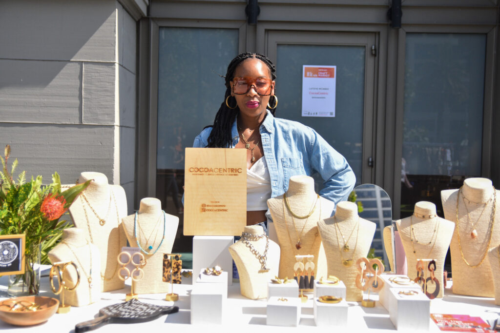 LaToya McInnis poses with jewelry at CocoaCentric's stand at Foodwise's Pop-Ups on the Plaza event at the Ferry Plaza Farmers Market in San Francisco