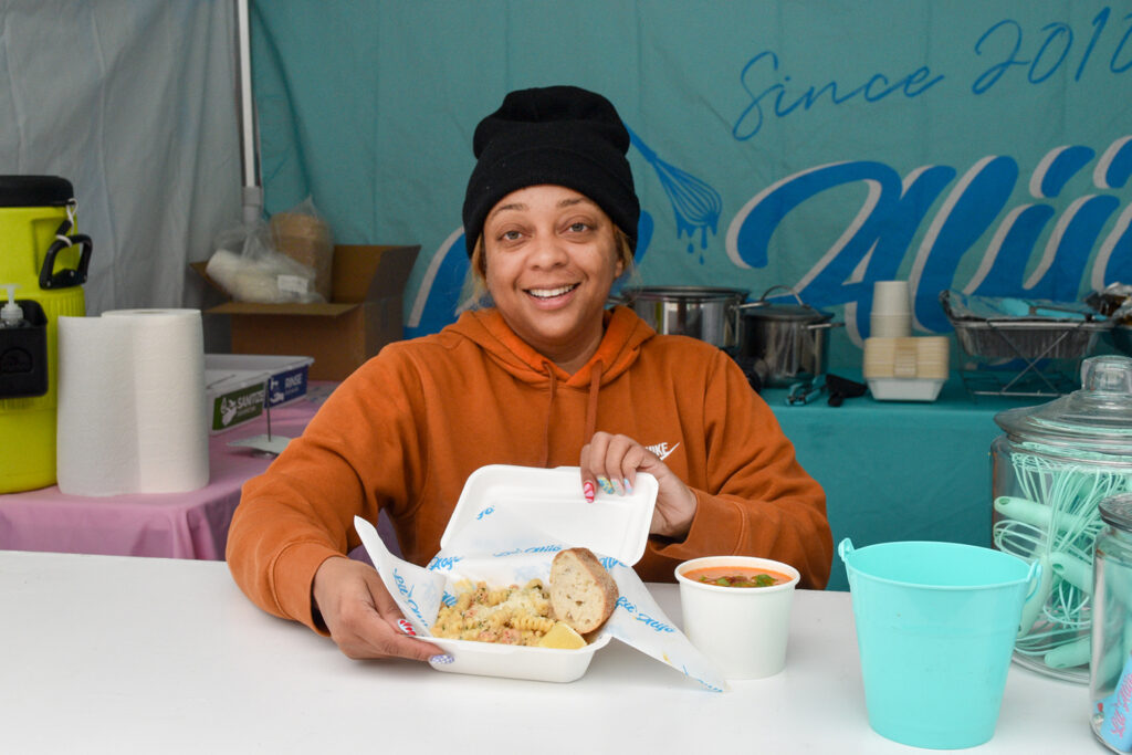 Alisha Wilson smiling and holding food at Lil' Alijo's booth at FPFM, 2023