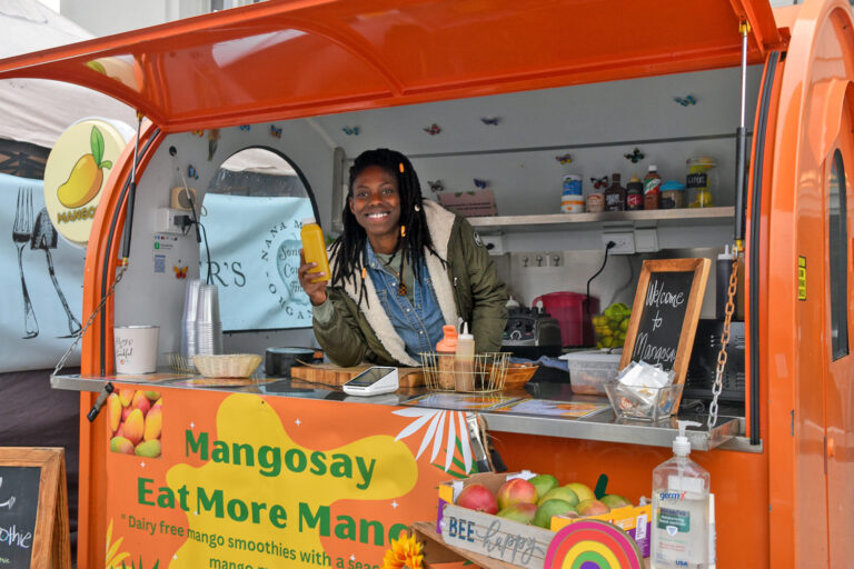 Sierra Young holding a bottle of mango juice in Mangosay's mobile mango cart at FPFM