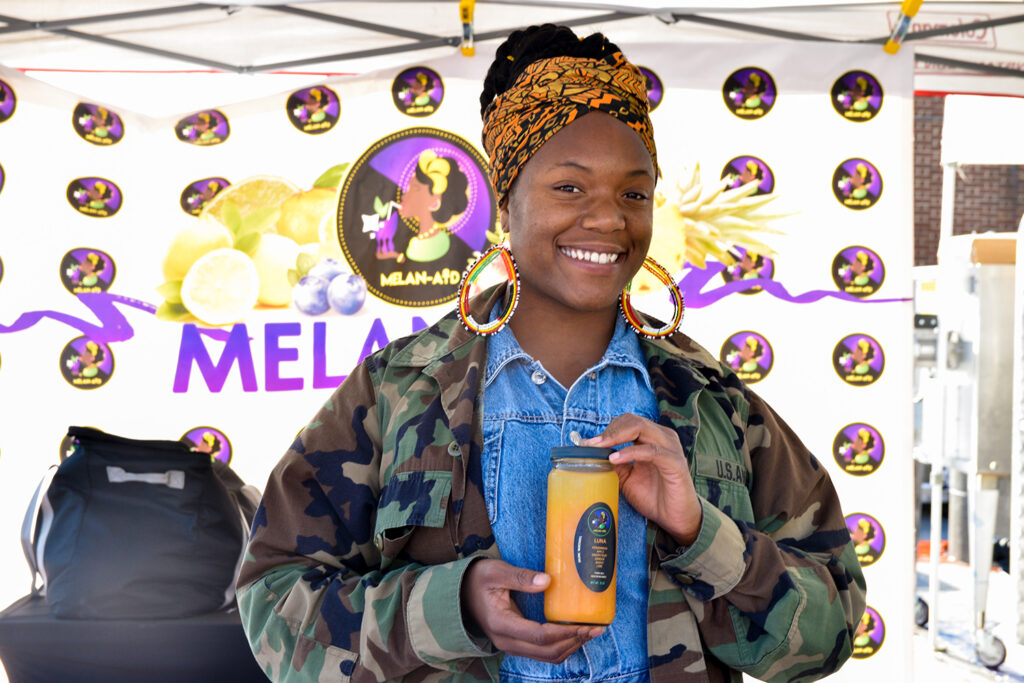 Jameelah Lane holding juice at Melan-Aid's stand at POP, 2022