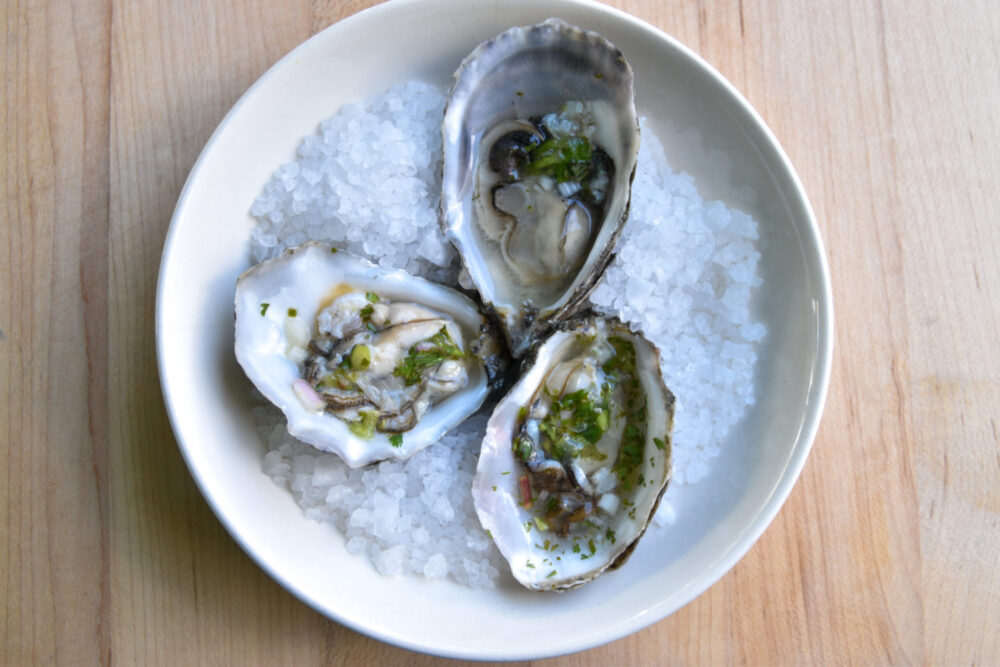 three oysters on a half shell, nestled in ice