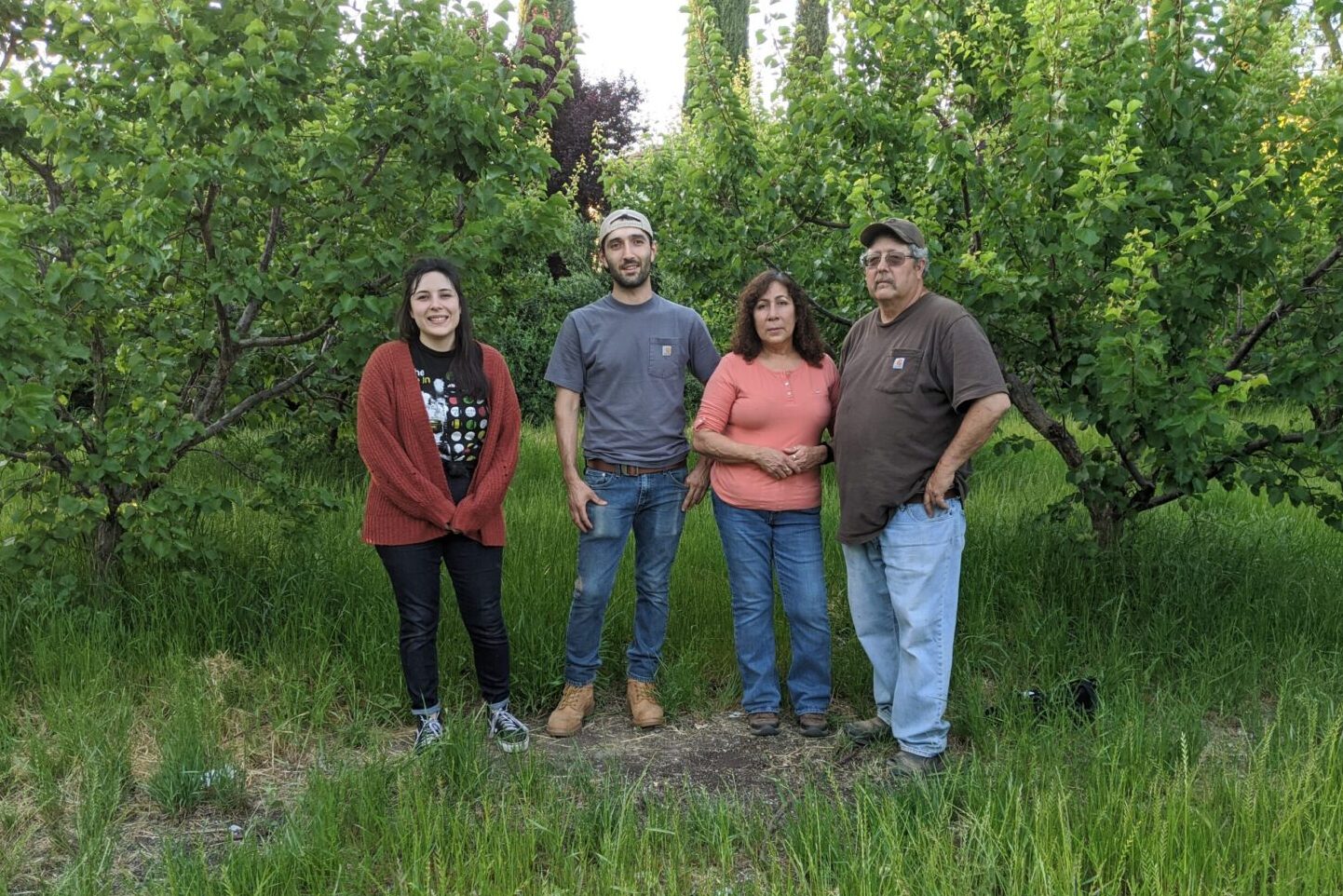 Winters Fruit Tree family photo. The Carter family poses in front of lush green trees.