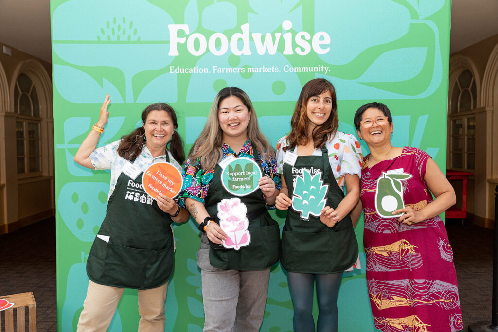 Photo of Foodwise volunteers and staff in front of a teal and green photo backdrop.