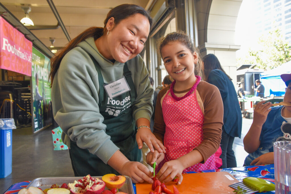 Foodwise intern Christine Kim poses with a student in the Foodwise Kitchen at the Ferry Plaza Farmers Market in San Francisco.