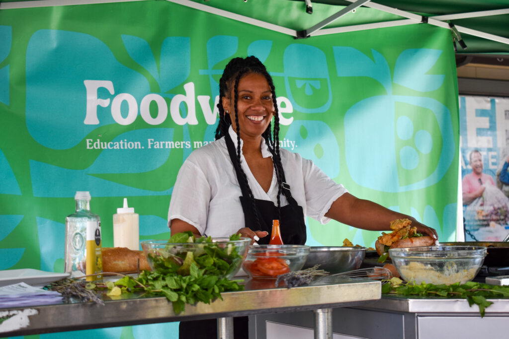 Tiffany Carter poses in front of a teal and green background at the Foodwise Classroom at the Ferry Plaza Farmers Market in San Francisco.