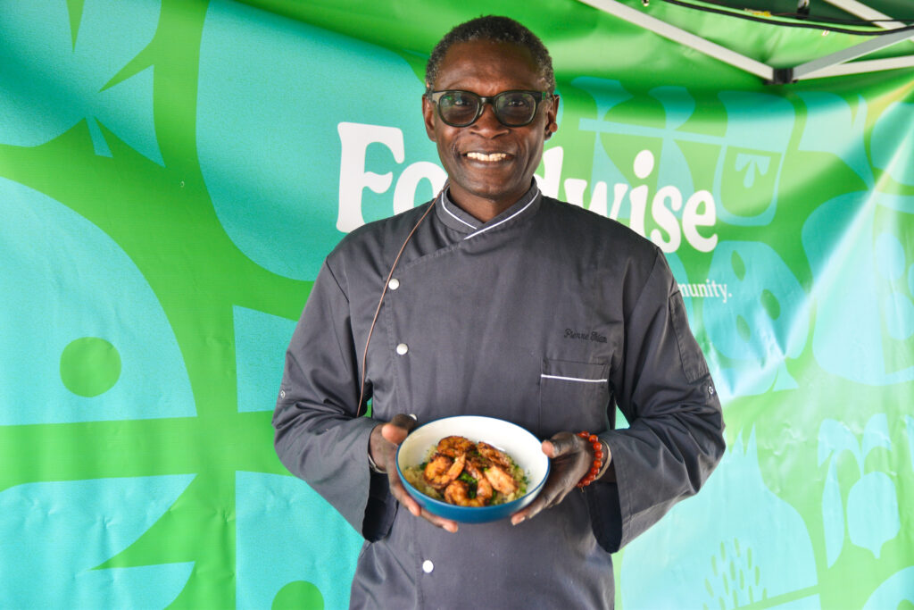 Pierre Thiam holds shrimp and fonio grits at the Foodwise Classroom at the Ferry Plaza Farmers Market in San Francisco.