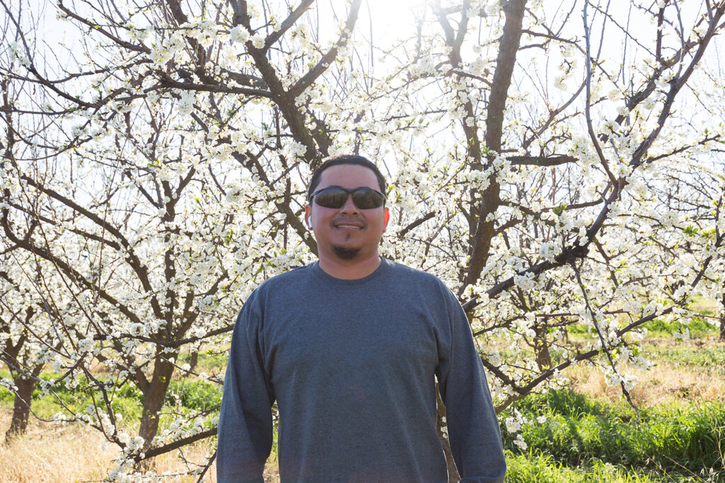 Someone poses in front of blossoming trees.