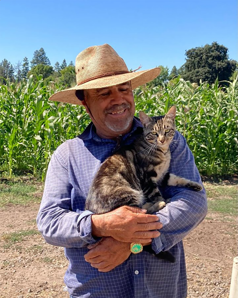 A farmworker holds a cat on a farm.