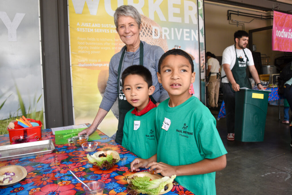 A woman and two kids pose for a picture during a cooking lesson at the farmers market.