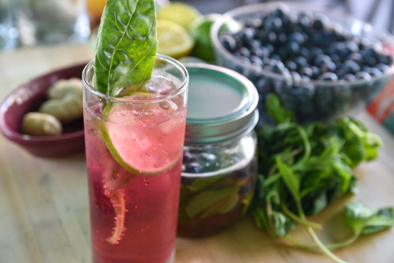 Photo of an iced beverage, garnished with citrus slices and herbs