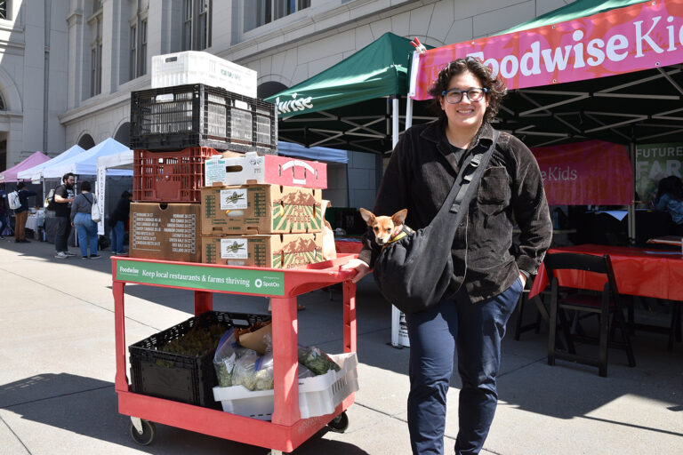A photo of someone posing with a chef's cart at the farmers market