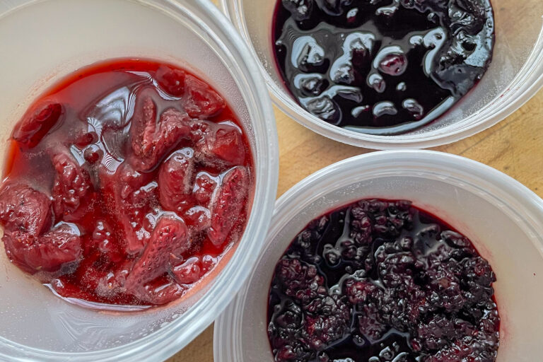 Three containers, each with different fruit jams.
