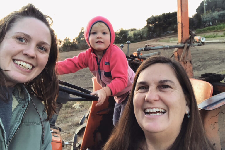 A selfie of three people smiling on a farm
