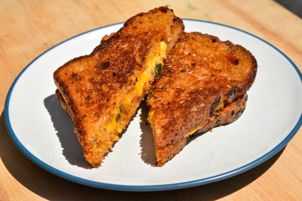 A plate of grilled cheese, cut into triangular halves.