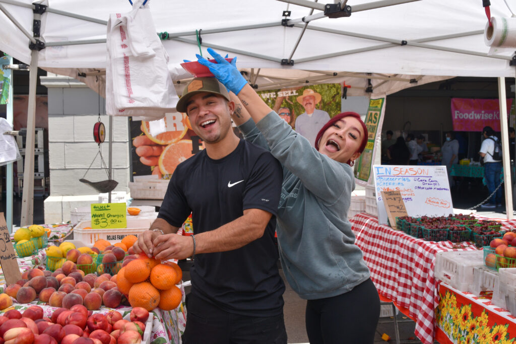Ramon and Diana Rojas pose with fruit at Rojas Family Farms' stand at the Ferry Plaza Farmers Market.