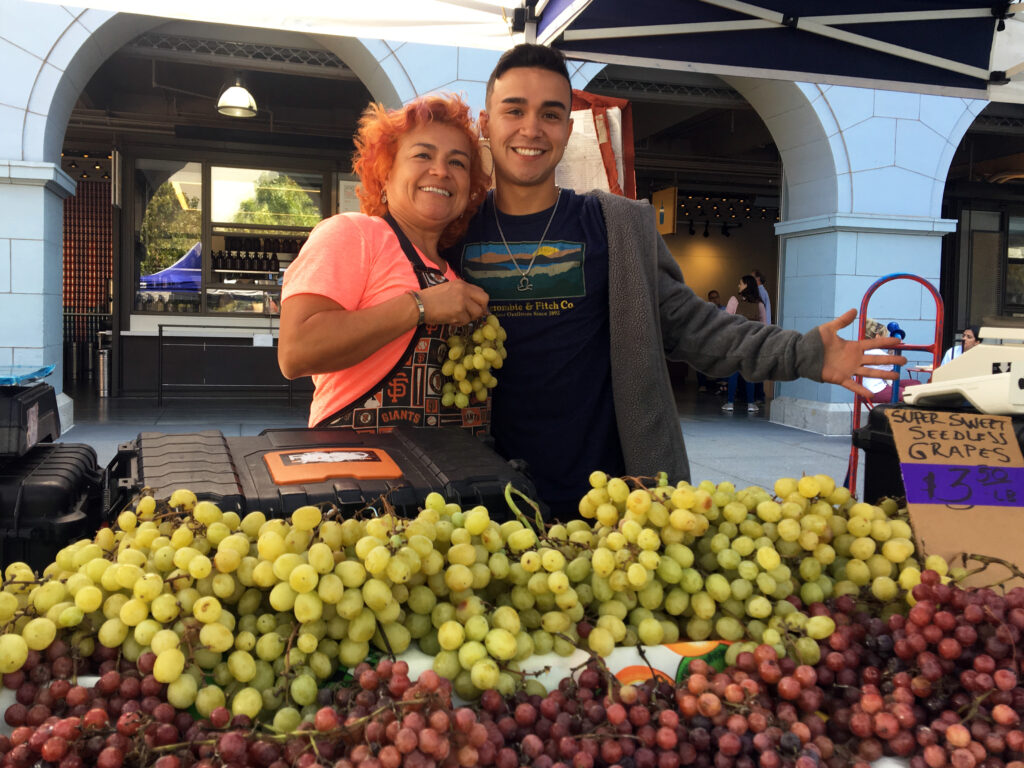 Sonia and Ramon Jr. Rojas pose with grapes at Rojas Family Farms' stand at the Ferry Plaza Farmers Market.