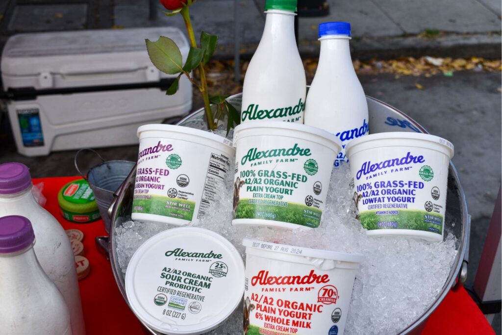 An metal ice bucket holding 4 containers of yogurt, 1 tub of sour cream, and 2 bottles of milk.